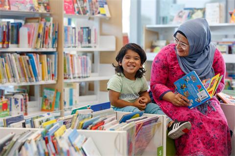 A parent and child reading together at a library